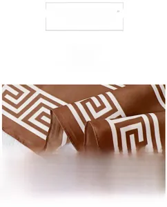 Close-up of caramel brown silk scarf with white Greek key pattern and satin finish