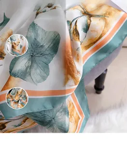 Dettaglio di elegante sciarpa in finta seta con foglie di ginkgo arancioni e blu