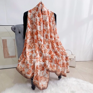 Detail of elegant floral silk scarf with orange flower pattern and dark brown border