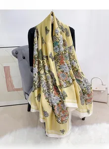 Detailansicht eines gelben Seidensatinschals mit Blumenmuster und weißen Streifen an den Rändern