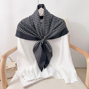 Elegant black and white silk square scarf featuring classic monogram patterns on a shirt