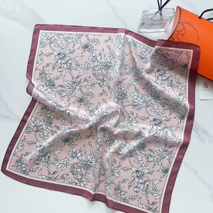 Detailed texture of pink silk scarf with black and white floral line art and satin finish