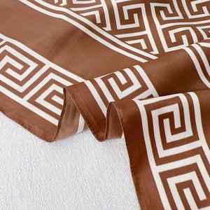 Detailed view of brown satin scarf with white Greek key geometric pattern and soft drape