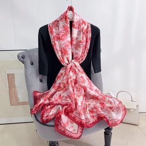 Detailed texture of a floral silk-like scarf draped elegantly on a stylish grey velvet chair