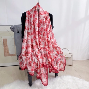 Detail of red floral satin scarf with silk-like texture and elegant drape over a chair