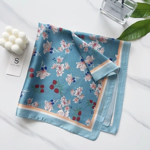 Detailed flat lay of 58cm floral silk scarf with lily print on white marble background