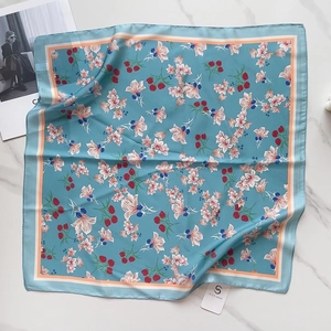Close-up of light blue silk square scarf with floral pattern on white marble surface