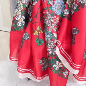 Detail eines roten Blumen-Chiffon-Schals mit elegantem weiß gestreiftem Rand und Textur
