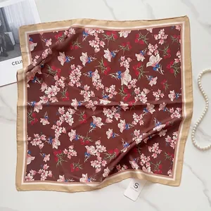 Detailed flat lay of a silk floral square scarf with lilies on a marble background