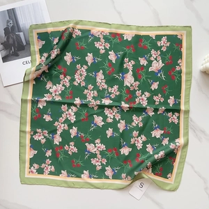 Flat lay of floral silk square scarf in dark green on marble table with fashion magazine