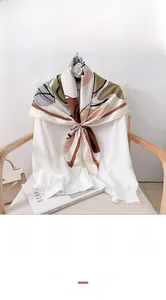 Detailed view of large square silk scarf with geometric pattern and rope trim on a white shirt