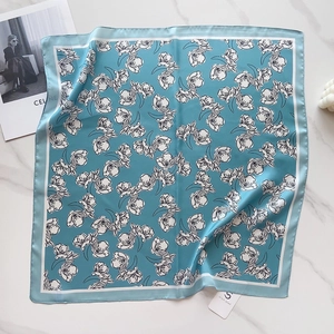Detailed macro view of the teal floral satin scarf featuring a classic printed pattern