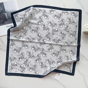 Detail of square silk scarf with black and white floral prints on marble background
