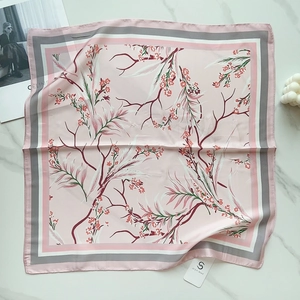 Detail view of pink silk floral square scarf with plum blossom pattern and brand tag