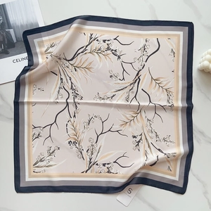 Detail of silk-like square scarf with floral pattern and striped border on marble