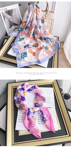 Détail de foulards en soie à motifs floraux sur un cadre doré et un magazine chic