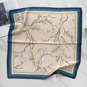 Detailed view of square faux silk scarf with orange floral prints and colorful borders