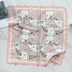 Detail of square silk-like scarf featuring pink tulip floral pattern and plaid edges