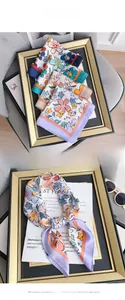 Detailed close-up of light faux silk scarf with colorful floral prints and contrast edges