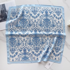 Close-up of a 58cm silk-feel square scarf with blue baroque patterns on smooth satin fabric