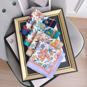Elegant floral square silk scarves in four colors displayed in a vintage golden frame