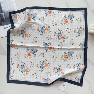 Flat lay of silk-like floral square scarf with blue borders on marble background