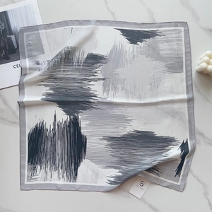 Detailed view of elegant floral silk scarf with abstract brushstroke patterns on marble