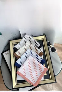 Silk-like square scarves with polka dots displayed on a velvet sofa with accessories