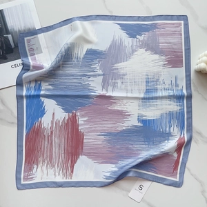 Detailed close-up of a 58cm square silk scarf with blue abstract floral patterns on marble