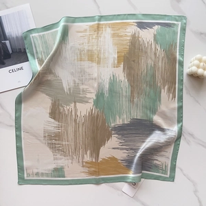 Detail view of a floral silk scarf on marble background with elegant lifestyle props