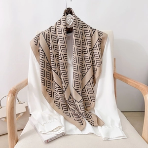 Elegant beige geometric silk scarf with black monogram patterns on a white shirt