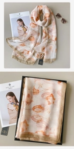 Dettaglio di un elegante foulard in seta stampata a fiori con ciondolo in metallo