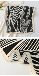 Detail of silk-feel scarf featuring black and white geometric leaf patterns and contrast edges