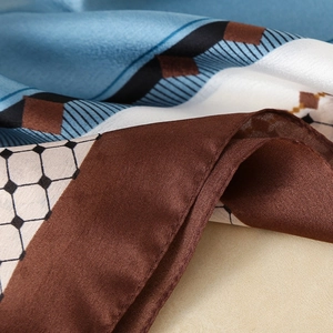Elegant silk-like scarf featuring geometric patterns and fine stitching in soft blue and brown