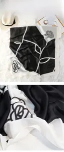 Detail of silk-like scarf with black and white rose floral print and glossy texture