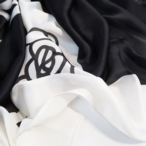 Elegant black and white silk scarf featuring large camellia patterns and satin finish