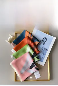 Détail de foulards carrés élégants en imitation soie présentés dans un cadre en métal doré