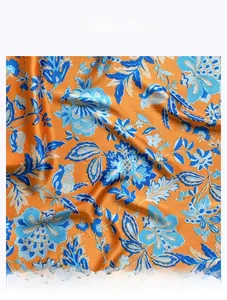 Close-up of vintage orange silk scarf with blue floral pattern and smooth texture