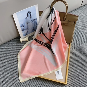 Élégant foulard carré rose en soie avec motifs abstraits noué sur un sac à main