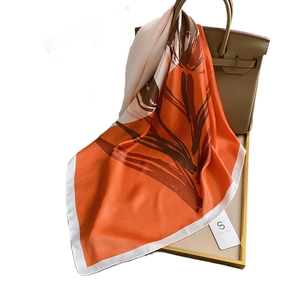 Carré de soie élégant avec imprimé feuilles orange et marron drapé sur un sac à main