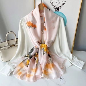 Elegant silk-style printed scarf in apricot pink featuring golden autumn landscape patterns