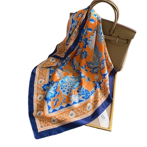 Elegant vintage floral print silk scarf in orange and navy blue tied on a handbag