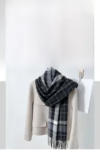 Detailed view of British style plaid cashmere scarf with soft fringes on wool coat