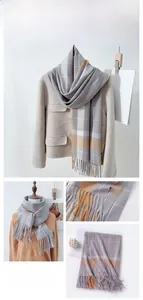 Detailed view of the gray and orange plaid pattern and tassel fringe on a warm scarf