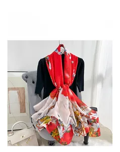 Detail of red floral silk satin scarf featuring white blossoms and berry patterns