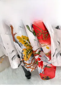 Detailed close-up of floral print silk scarf fabric on white faux fur background
