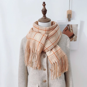 Classic orange and white plaid cashmere-like scarf with fringe on a beige coat