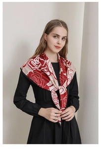 Detailed texture of a silky floral shawl with red roses and elegant black hem detail