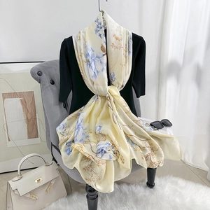 Elegant floral silk satin scarf in beige with blue flower print on a black sweater