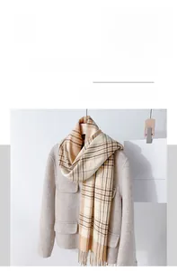Details eines beige-braunen Karo-Schals mit Fransen auf einem Wollmantel für den Winter
